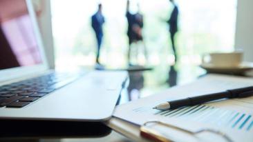 Whistleblowers: a laptop, a document and a pencil, and people talking in the background