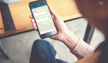 Man holding a phone that shows a conversation Man holding a phone that shows a conversation